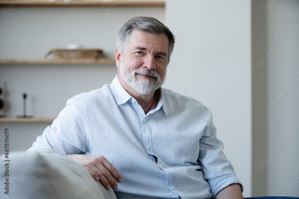 Portrait of happy mature man sitting on sofa at home. Portrait of happy mature man sitting on sofa at home.