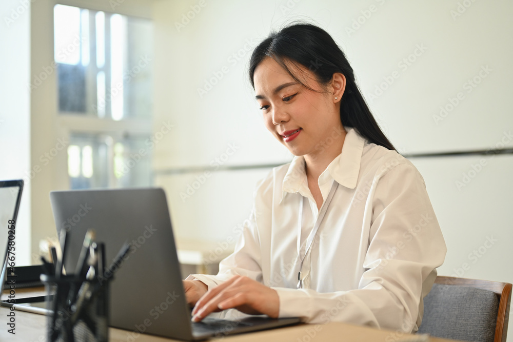 Charming asian woman working on online marketing, using laptop computer at workplace Charming asian woman working on online marketing, using laptop computer at workplace