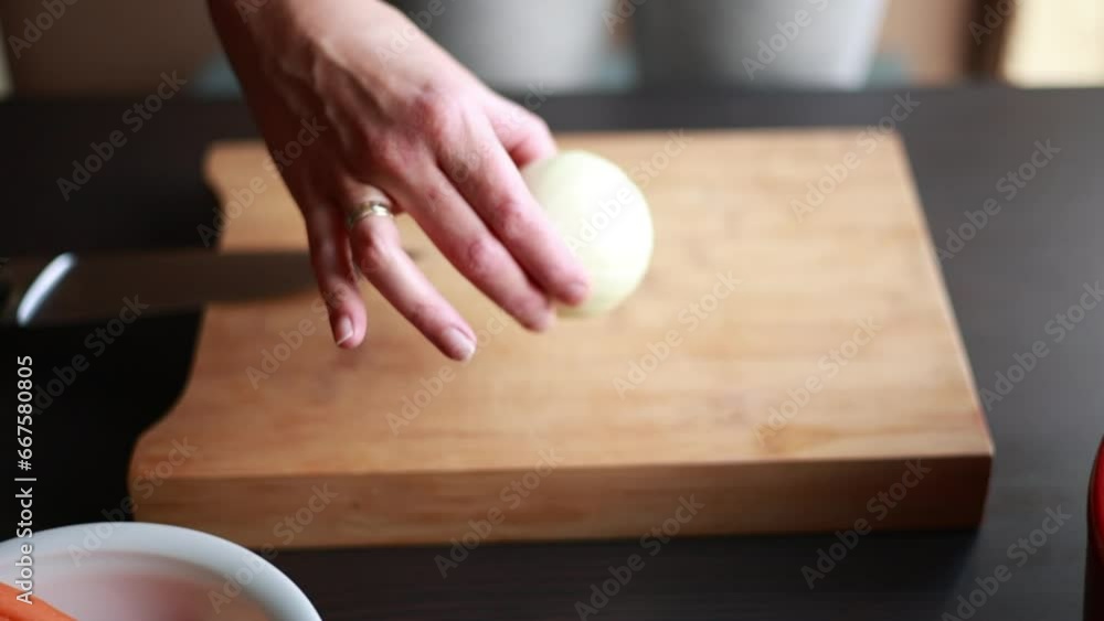 woman hands cutting onion for a soup base close up on wooden board at home woman hands cutting onion for a soup base close up on wooden board at home