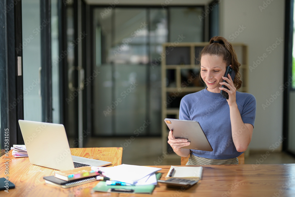 Businesswoman talking on the phone with friend or colleague while checking documents in modern office Businesswoman talking on the phone with friend or colleague while checking documents in modern office
