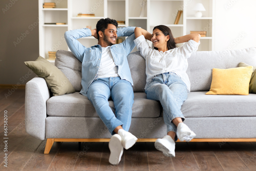 Cheerful Indian couple enjoying a moment on a couch in a cozy living room Cheerful Indian couple enjoying a moment on a couch in a cozy living room