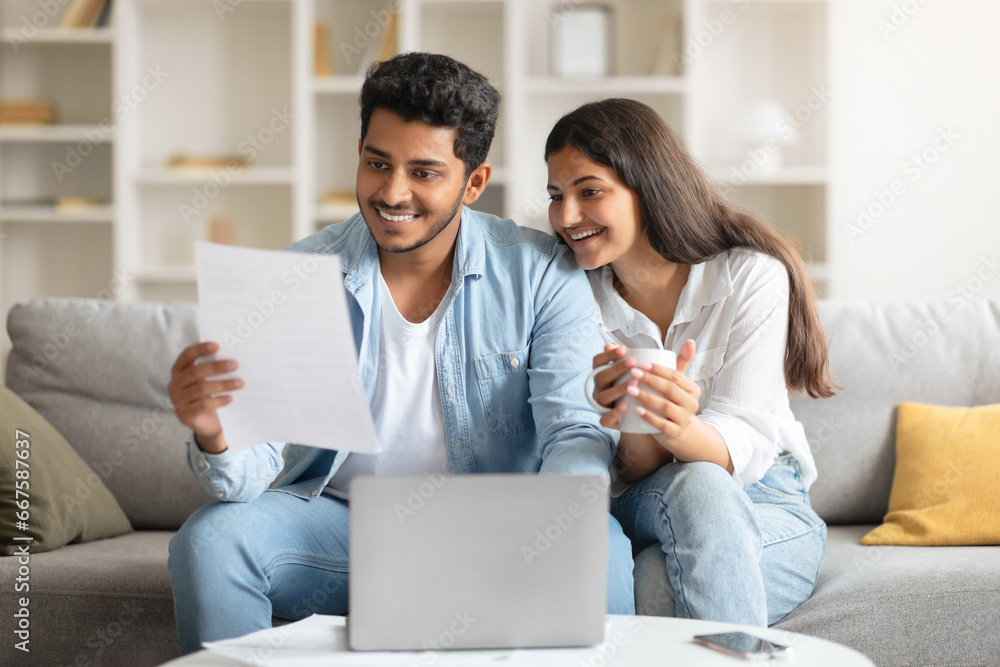 Happy Indian couple reviewing a document with a laptop Happy Indian couple reviewing a document with a laptop