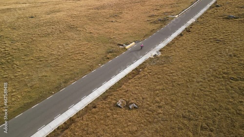 Aerial drone shot of professional woman cyclist riding bicycle on empty mountain road.Active sports concept.Cycling outdoors.Exercise on road bike.Cycling and healthy lifestyle concept.Training a bike