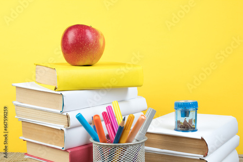 Books stacking. Books on wooden table and yellow background. Back to school. Copy space for ad text.