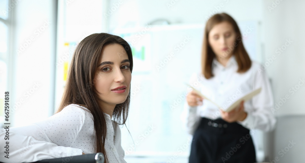 Portrait of smart businesswoman sitting at modern workplace and looking at camera with calmness. Joyful lady discussing important charts and graphs. Accounting office concept