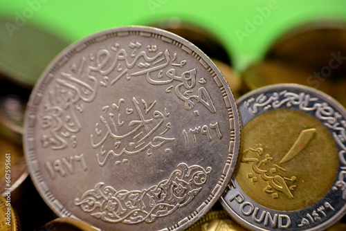 A new and old Egyptian One 1 EGP LE pound coins, a commemorative silver coin year 1976 AD, 1396 AH of King Faisal Bin AbdulAziz Al Saud and a current 1LE coin, reverse sides, selective focus photo