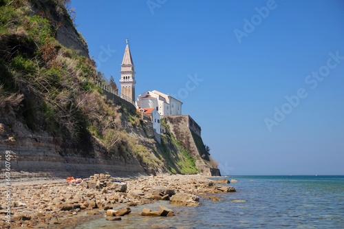Steep rocky shore of the Adriatic Sea with a view of the Catholic Church and bell tower in Piran  Slovenia.
