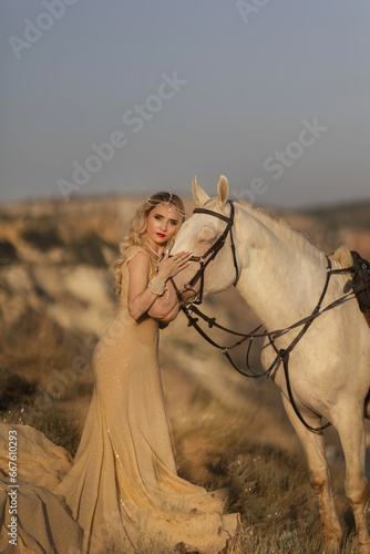 Cheerful bright girl leans on the horse, eyes closed, hand on the hair. Fashion blonde in the red dress. photo