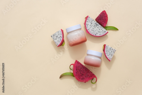 Two jars transitions from white to pink, adorned with slices of red and white dragon fruit on a pastel pink background. Depicting cosmetics infused with dragon fruit extract.