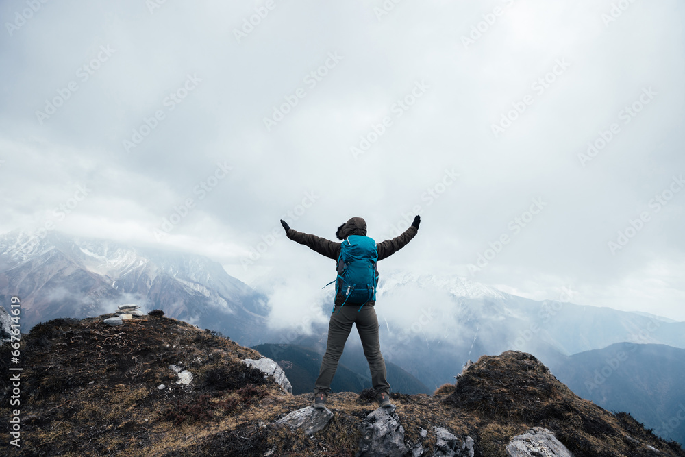 Woman hiker enjoy the view on mountain top cliff edge face the snow capped mountains in tibet Woman hiker enjoy the view on mountain top cliff edge face the snow capped mountains in tibet