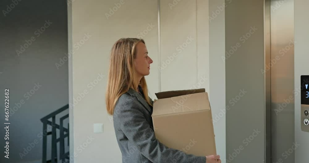 Happy woman with cardboard box entering into elevator Happy woman with cardboard box entering into elevator