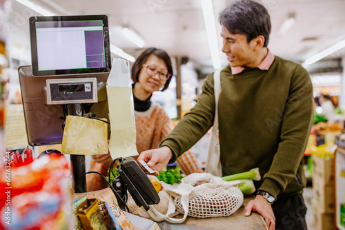 Man buying fresh produce from woman at supermarket counter photo