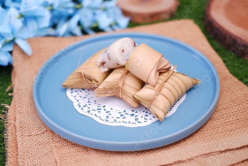 Lepet or Leupeut is a type of snack made from glutinous rice mixed with peanuts, cooked in coconut milk, then wrapped in coconut leaves. Close up view photo