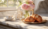 Cup of tea with flowers and croissants on a marble tabletop in the morning sun