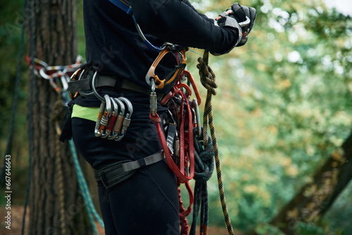 Close up particle view. Man is doing climbing in the forest by use of safety equipment