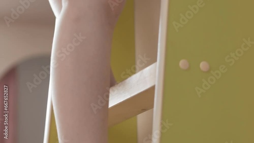 The child's legs climb the steps of a green bunk bed. Improvement of the children's room.
