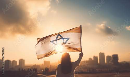 Woman raising flag of Israel. feminism,human rights,conflict Palestina concept. Jewish girl standing with the flag of Israel on the amazing valley and city and sky background. Memorial day-Yom,