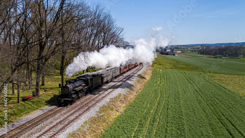 An Antique Steam Passenger Train Traveling Thru Farmlands, With Crops Planted, Blowing Smoke on a Sunny Spring Day