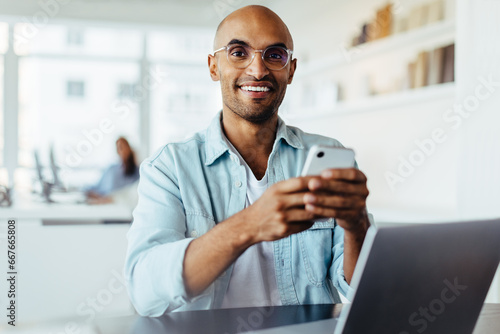 Business man using a smartphone while sitting with a laptop