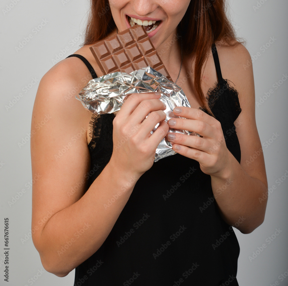 Φωτογραφία frau beisst unerkannt gesicht nur mund und zähne in eine tafel schokolade nasche