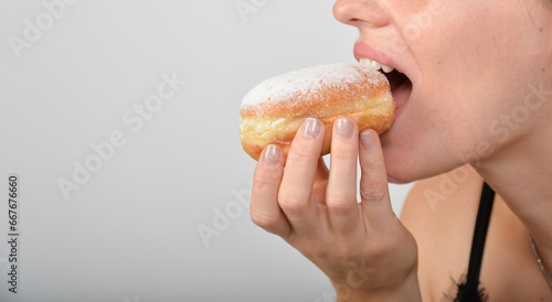 frau beisst herzhaft genüsslich in einen krapfen pfannkuchen berliner - unerkannt closeup nur mund hand essen abbeißen photo