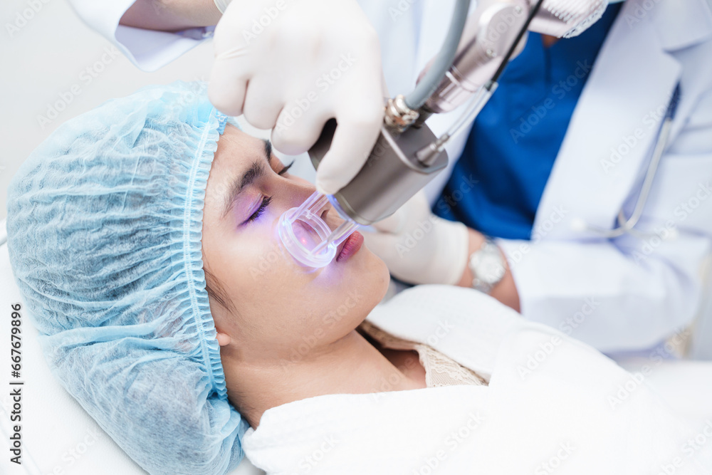 Side view of asian woman getting resurfacing laser fraxel dual and ultrasound face treatment in medical spa center. skin rejuvenation concept Side view of asian woman getting resurfacing laser fraxel dual and ultrasound face treatment in medical spa center. skin rejuvenation concept