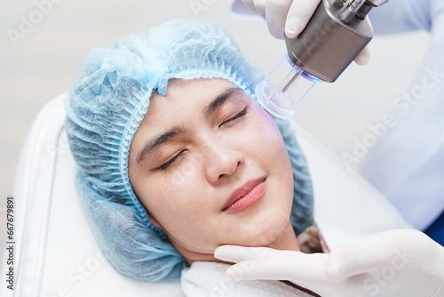 Side view of asian woman getting resurfacing laser fraxel dual and ultrasound face treatment in medical spa center. skin rejuvenation concept photo