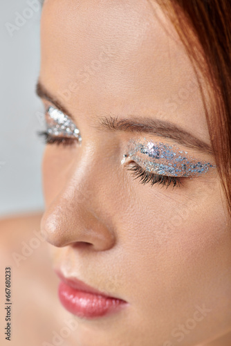 close up view of beautiful young woman with holiday makeup, shimmery eye shadow and closed eyes