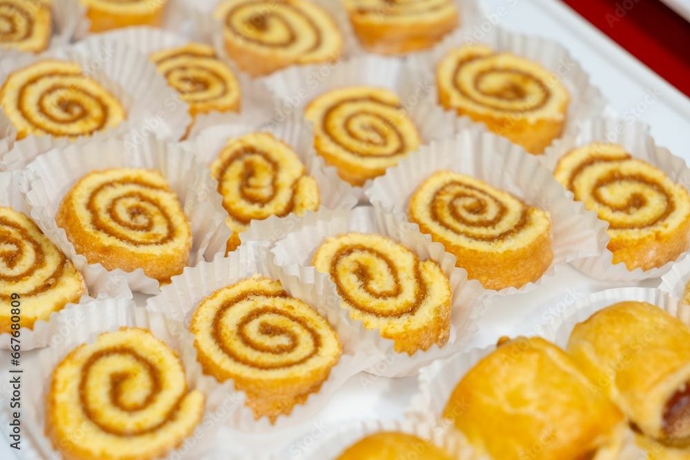 many different kinds of cookies on white trays next to a plate many different kinds of cookies on white trays next to a plate