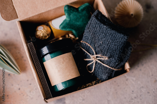 Billede på lærred Christmas box with presents - candle in dark jar, chocolate candies, cozy grey socks and festive decoration