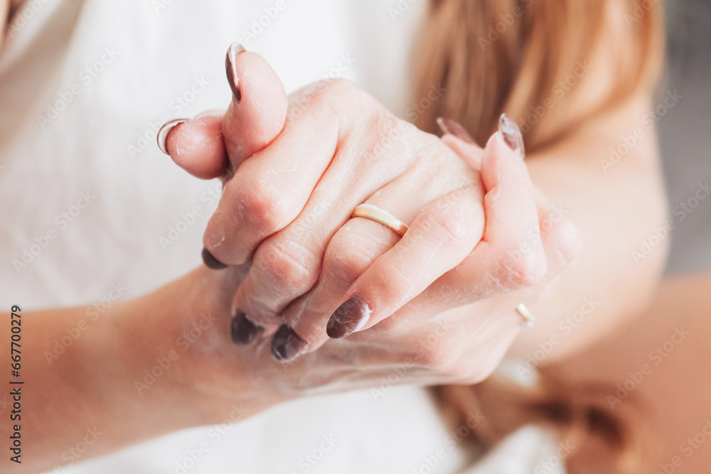 Fototapeta premium Skin care background. Hand cream use. Closeup of wet skin. Cosmetics background. Hands moisturizing. Body lotion on hands. Caucasian female lifestyle applying cream background.