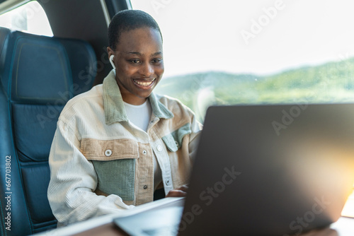A young woman in train using laptop. Cropped shot of an attractive young woman sitting and wearing earphones while using her laptop in the train. photo