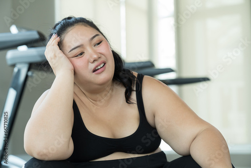 Fototapeta Naklejka Na Ścianę i Meble -  Exhausted young Asian woman after workout in fitness club. Young overweight woman hard work to lose weight in gym