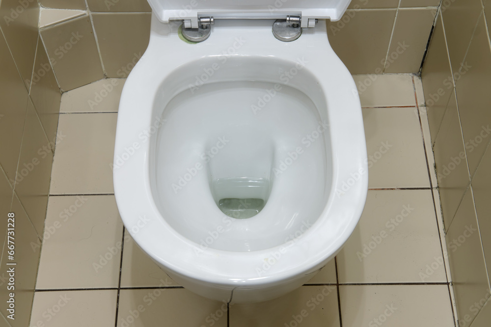 Fototapeta premium The washroom boasts a modern design with a clean toilet bowl and beige ceramic tiles.