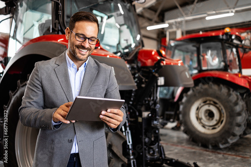 Portrait of tractor salesman holding tablet computer at dealership.