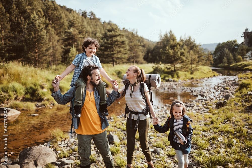 Happy young family walking next to a river in nature