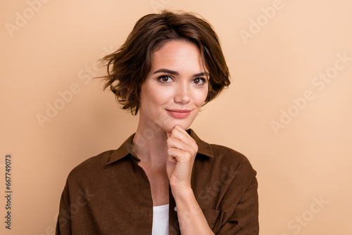 Photo of good mood woman with bob hairstyle dressed brown shirt hold finger on cheen think business isolated on beige color background