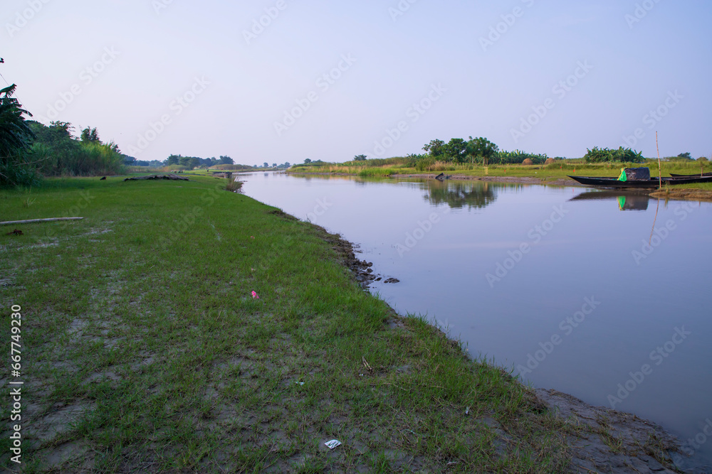 Canal with green grass and vegetation reflected in the water near Padma River in Bangladesh