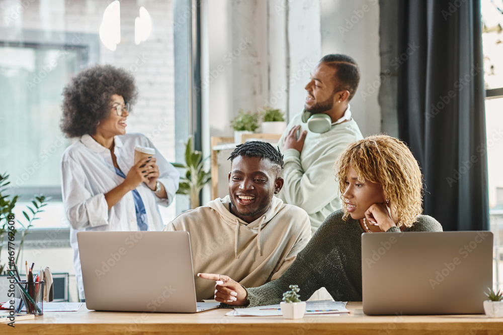two cheerful young people working on laptop with their friends on backdrop, business concept two cheerful young people working on laptop with their friends on backdrop, business concept