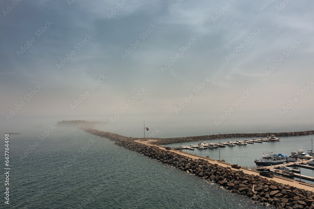 Rock Marina Wall Leads Out to Island Covered by Fog