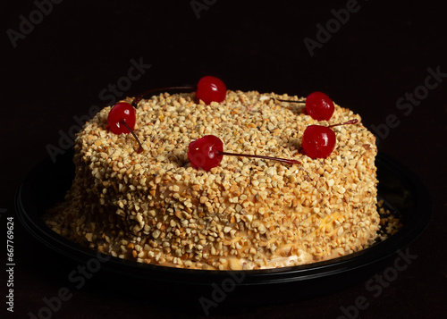 Peanut cake or pie or torta paulista with cherrys on top in a dark black background