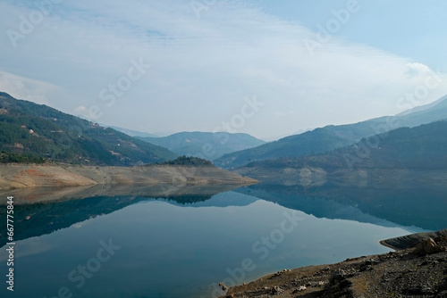 Beautiful view of mountain lake on a calm foggy day with gray cloudy skies. Copy space, background.