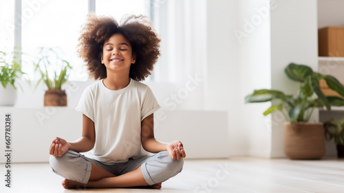A candid shot of a joyful African American girl practicing yoga at home, radiating positivity with a serene smile, white home background, blurred background, with copy space