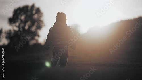 Child walking in a valley in the atardecer with silhouette