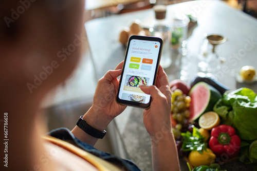 Close up of a woman looking for recipes on a smartphone app in the kitchen photo