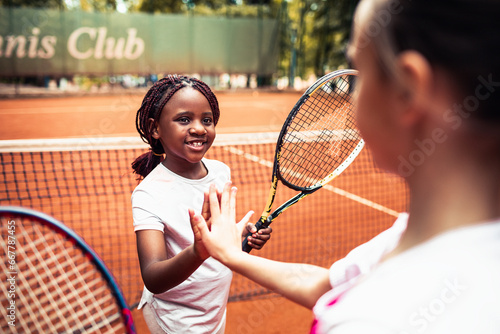 Young female tennis player high fiving her partner on a clay court
