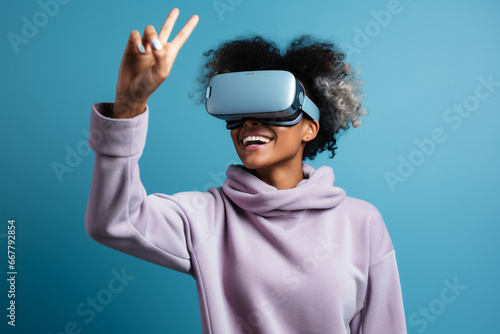 Young modern woman with augmented reality headset interacting with virtual content on plain blue background. Advertising image with bright colors and high-impact volumetric lighting.