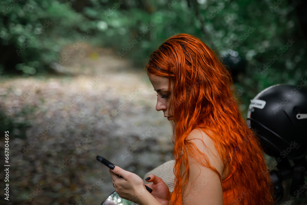 Beautiful girl with orange hair. Sunny summer day. Green trees.	
