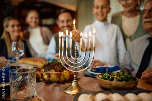 Quadro em tela Close up of Jewish kid lights candles in menorah during family gathering on Hanukkah