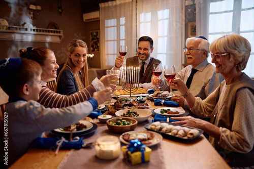 Happy multigeneration Jewish family toasting during traditional dinner on Hanukkah.